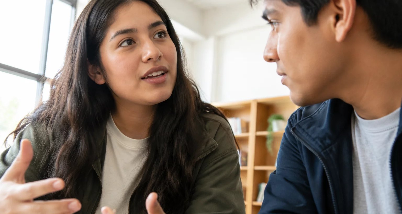 Dos personas conversando de cerca en una sala clara